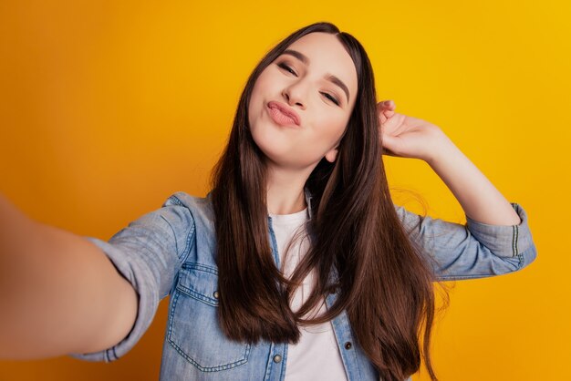 Primer plano de mujer hermosa joven tomando selfie enviar beso de aire posando sobre fondo amarillo