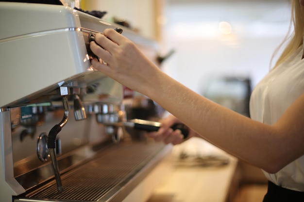 Primer plano de mujer hermosa con máquina de café en la cocina