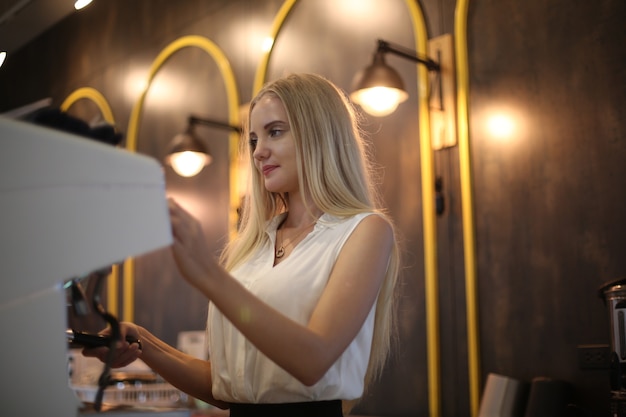 Primer plano de mujer hermosa con máquina de café en la cocina