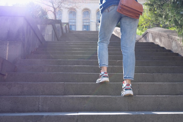 Primer plano de mujer en jeans subiendo escaleras empinadas turista femenina en ropa casual subiendo las escaleras