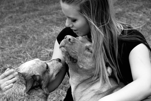 Foto primer plano de una mujer joven abrazando perros en el campo