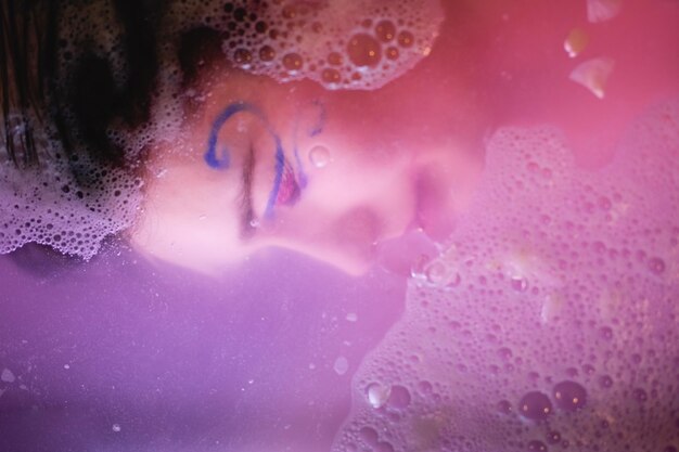 Foto primer plano de una mujer joven en agua rosada