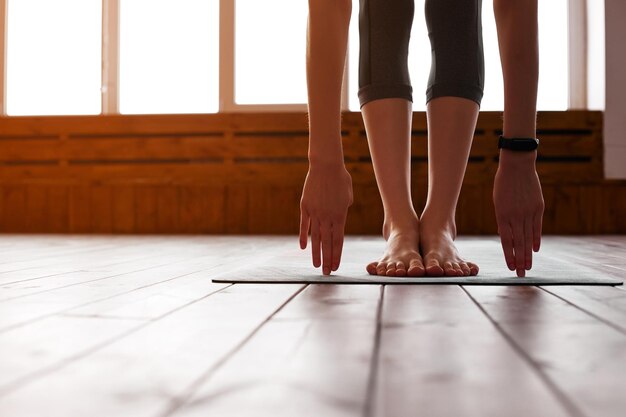 Primer plano de una mujer joven con una alfombra de ejercicio preparándose para el entrenamiento deportivo