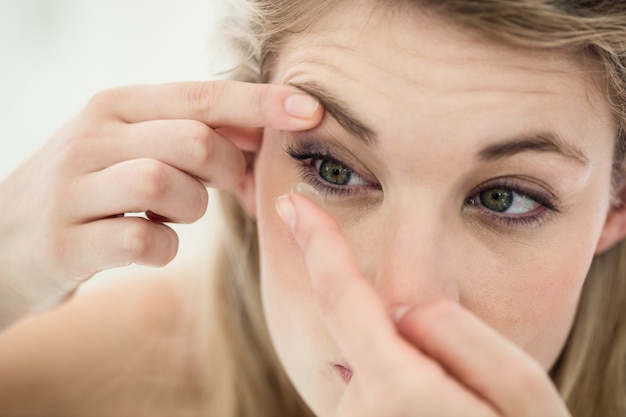 Foto primer plano de mujer joven aplicando lentes de contacto