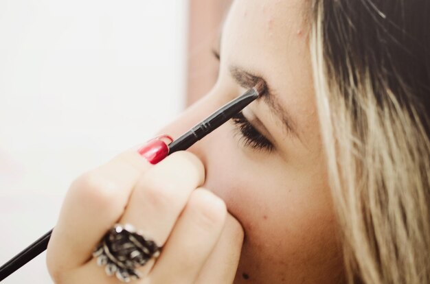 Primer plano de una mujer joven aplicando maquillaje en la ceja