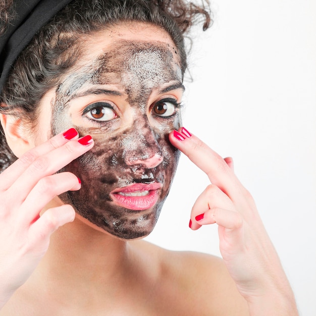 Foto primer plano de mujer joven aplicar mascarilla negra con sus dedos
