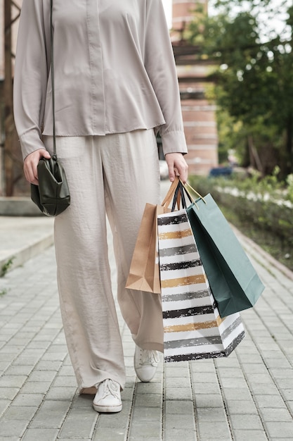 Primer plano de una mujer joven con bolsas de compras caminando por la ciudad al aire libre