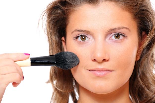 Un primer plano de una mujer joven y bonita poniéndose maquillaje natural