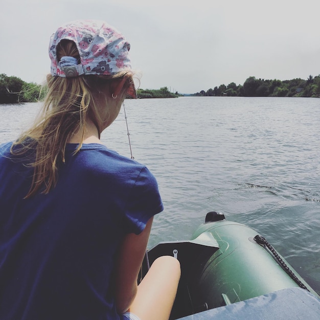 Foto primer plano de una mujer joven en un bote en el río contra el cielo