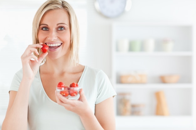 Primer plano de una mujer joven comiendo fresas