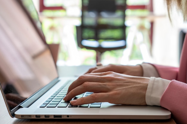 Primer plano de mujer joven escribiendo en su computadora portátil. Quedarse en casa, trabajar desde casa concepto.