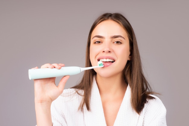 Primer plano de mujer joven feliz cepillarse los dientes Concepto dental Cepillo de dientes eléctrico