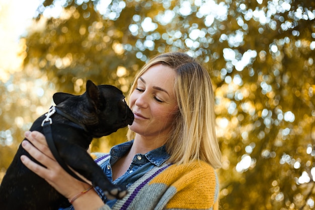 Primer plano de mujer joven feliz con perro al aire libre en otoño