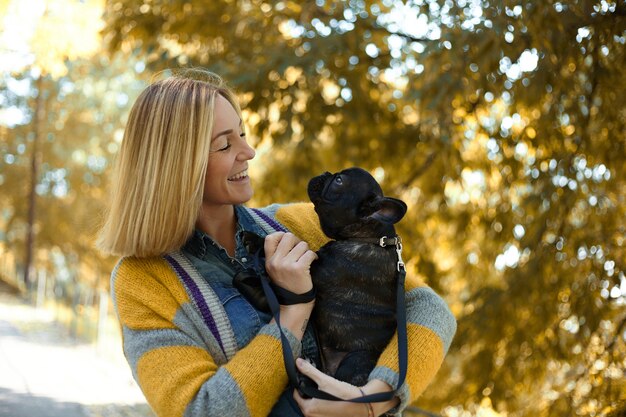 Primer plano de mujer joven feliz con perro al aire libre en otoño