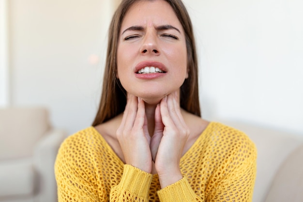 Foto primer plano de mujer joven frotando sus amígdalas inflamadas problema de amigdalitis recortada mujer con problema de glándula tiroides tocando su cuello niña tiene dolor de garganta