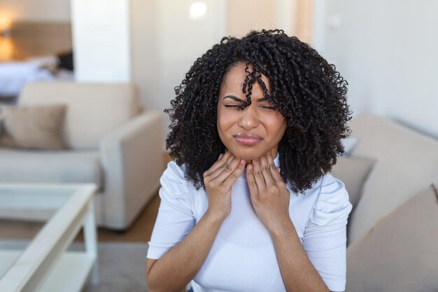 Primer plano de una mujer joven frotando sus amígdalas inflamadas problema de amigdalitis recortado Mujer con problema de glándula tiroidea tocando su cuello niña tiene dolor de garganta