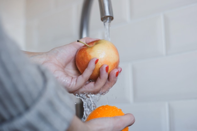 Primer plano de mujer joven lava frutas para prevenir la infección por coronavirus