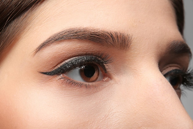 Primer plano de mujer joven con maquillaje elegante y pestañas largas