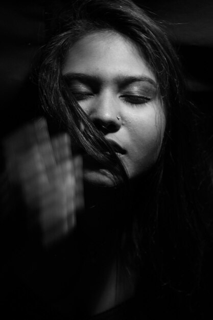 Foto primer plano de una mujer joven con los ojos cerrados en el cuarto oscuro