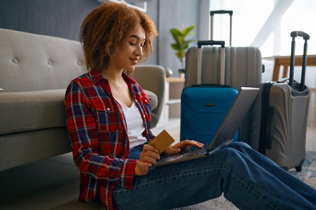 Primer plano mujer joven reservando viaje y haciendo compras en línea con tarjeta de crédito usando una computadora portátil