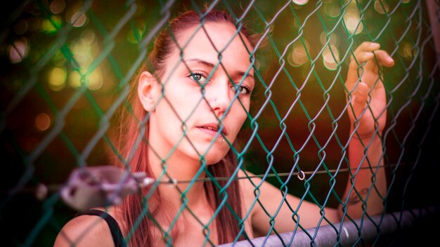 Foto primer plano de una mujer joven vista a través de la valla de cadena