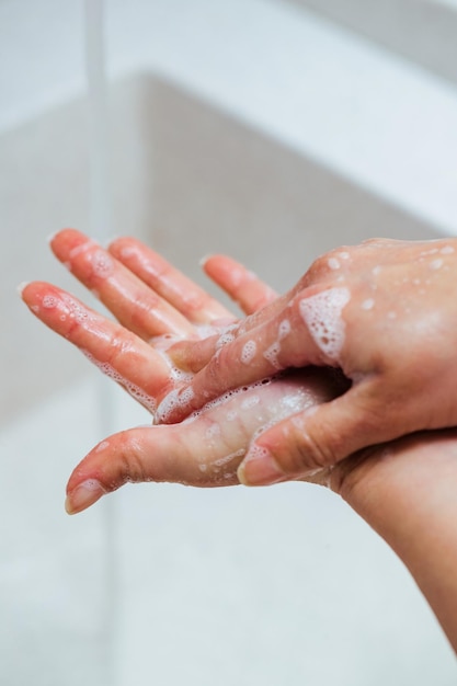 Primer plano de una mujer lavándose las manos con jabón en el baño.