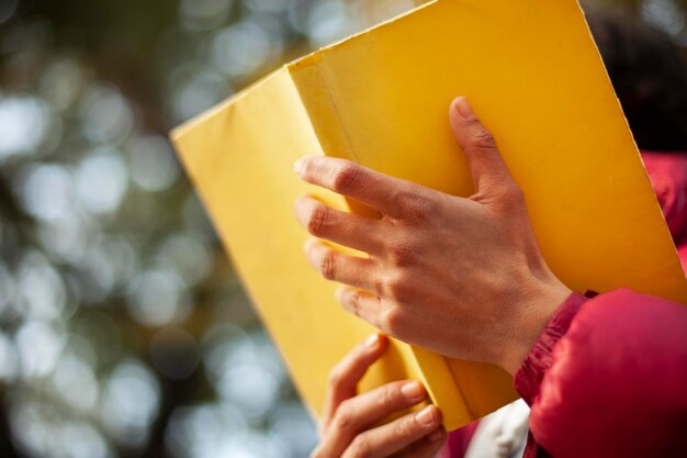 Primer plano de una mujer con un libro amarillo