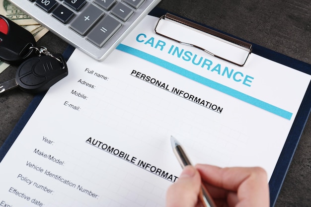 Primer plano de una mujer llenando a mano un formulario de seguro de automóvil