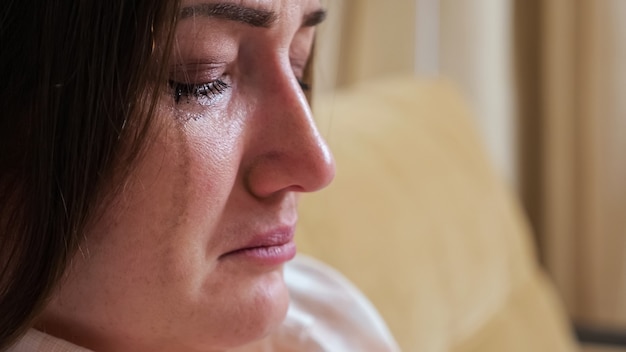 Primer plano de una mujer llorando, rímel borroso goteando por sus mejillas