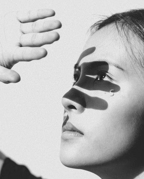 Primer plano de una mujer con la mano sobre un fondo blanco