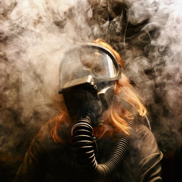 Primer plano de una mujer con una máscara de gas en el cuarto oscuro