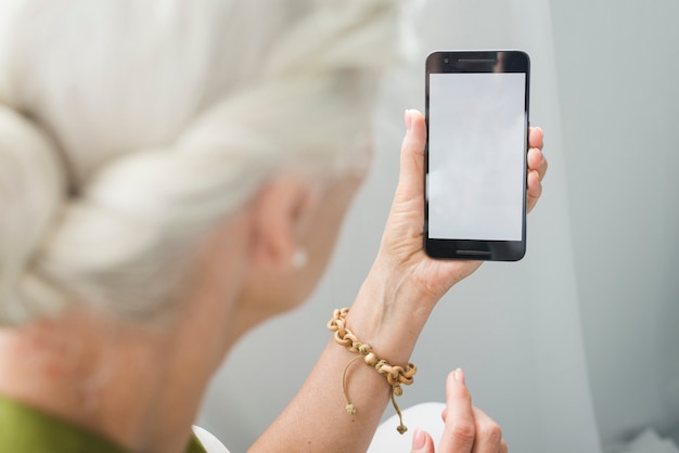 Primer plano, de, mujer mayor, mirar teléfono inteligente, con, pantalla en blanco