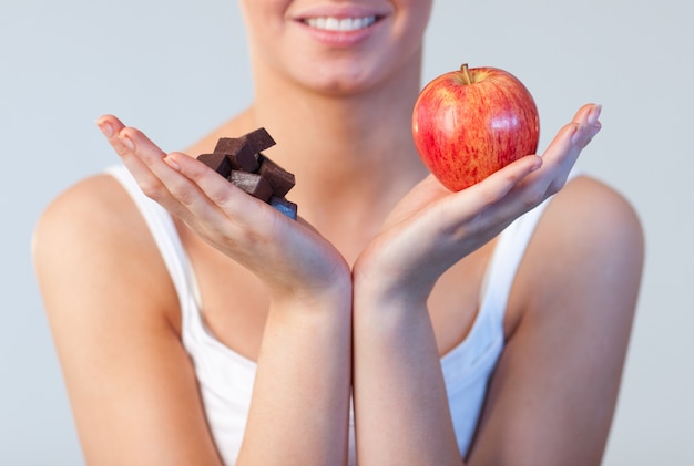 Primer plano de mujer mostrando chocolate y manzana se centran en chocolate y manzana