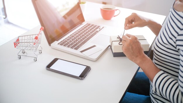 Primer plano de una mujer de negocios abriendo un regalo con una computadora portátil en la mesa