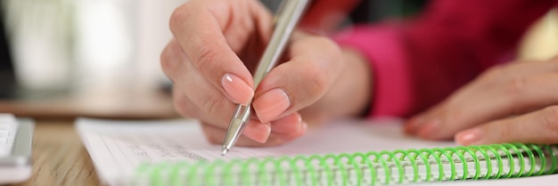 Primer plano de una mujer de negocios escribiendo en un cuaderno mientras está sentada en el escritorio de la oficina planificación de negocios