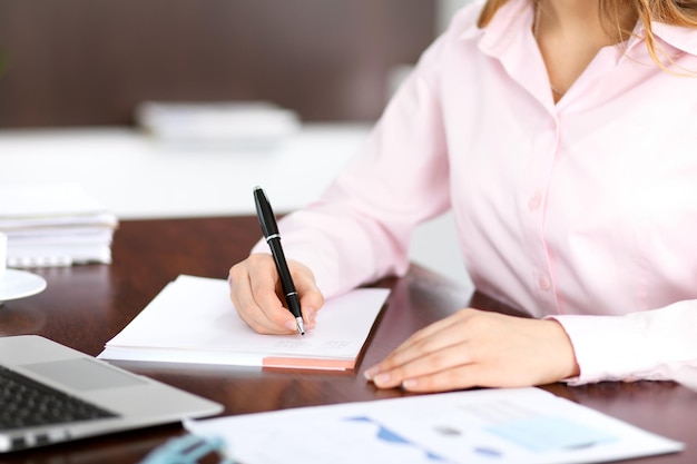 Primer plano de una mujer de negocios escribiendo en un cuaderno.