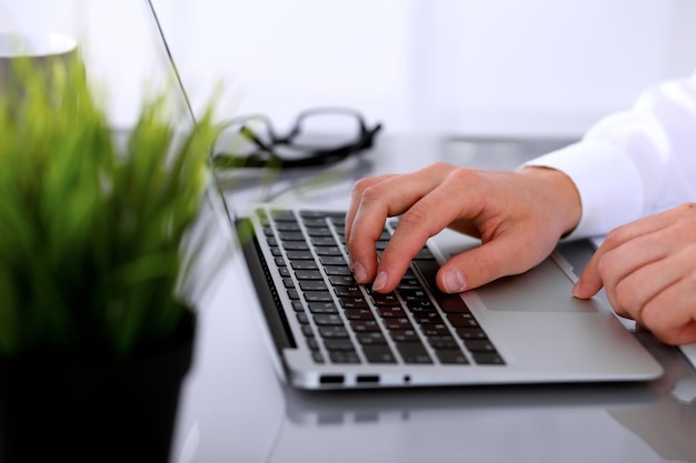 El primer plano de una mujer de negocios está escribiendo en una computadora portátil.