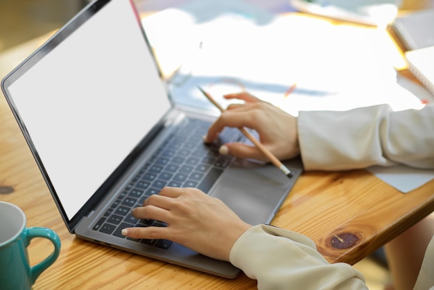 Primer plano, una mujer de negocios o estudiante universitario escribiendo en el teclado, usando una computadora portátil en la mesa