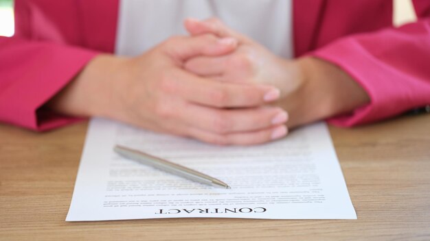 Primer plano de una mujer de negocios poniendo manos a la obra en un acuerdo de contrato y empleo de pluma plateada