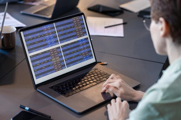 Primer plano de una mujer de negocios que trabaja en línea con un programa usando su computadora portátil durante la reunión en la mesa