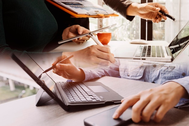 Primer plano de una mujer de negocios que trabaja con un teléfono inteligente y una computadora portátil y una tableta digital en una oficina moderna con un diagrama de icono virtual