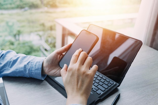 Primer plano de una mujer de negocios que trabaja con un teléfono inteligente y una computadora portátil y una tableta digital en una oficina moderna con un diagrama de icono virtual