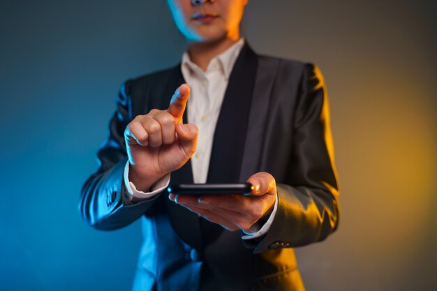 Primer plano de mujer de negocios con teléfono inteligente en traje negro. Elegante inteligente sobre fondo negro.