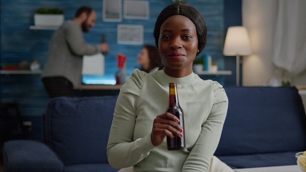 Primer plano de una mujer negra retrato mirando a la cámara bebiendo cerveza para el cumpleaños de un amigo