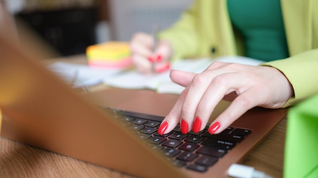 El primer plano de una mujer ocupada que trabaja desde casa usa una computadora portátil moderna para la comunicación web y