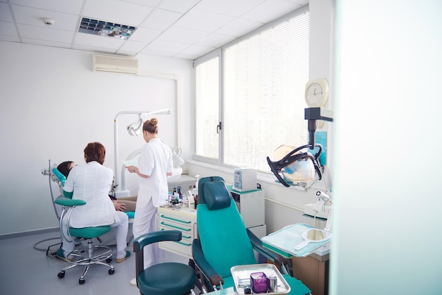 Primer plano de una mujer paciente en el dentista esperando ser revisada con la doctora en el fondo