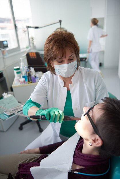 Primer plano de una mujer paciente en el dentista esperando ser revisada con la doctora en el fondo