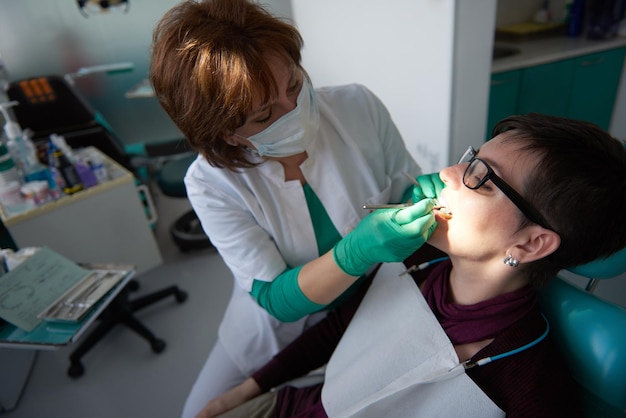 Primer plano de una mujer paciente en el dentista esperando ser revisada con la doctora en el fondo