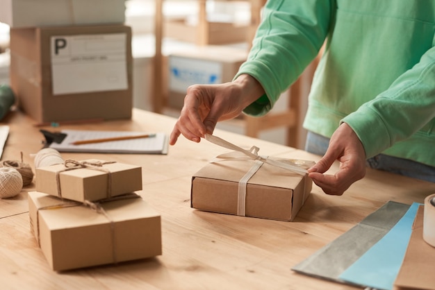 Foto primer plano de mujer de pie en la mesa y decorar cajas de regalo con cintas para vacaciones