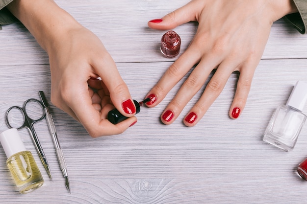 Primer plano de una mujer pinta sus uñas con laca roja